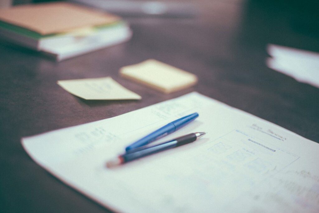 Pens and paper with notes arranged on a desk