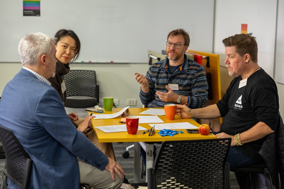 LLT workshop participants, discussing around a table.