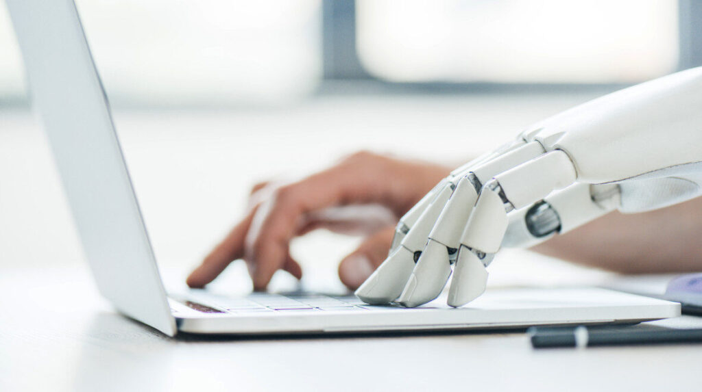 Decorative image of a robot and a human hand typing on a laptop
