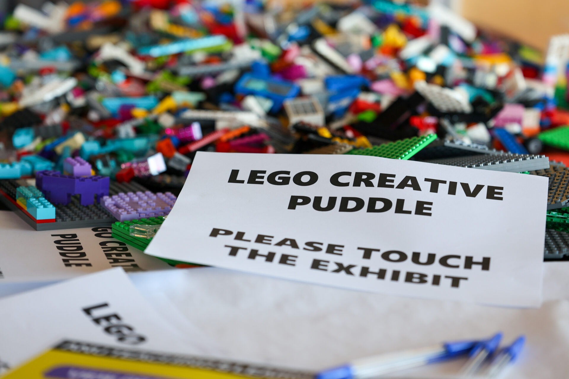 LEGO pieces and a sign inviting participants to explore the creative exhibit.